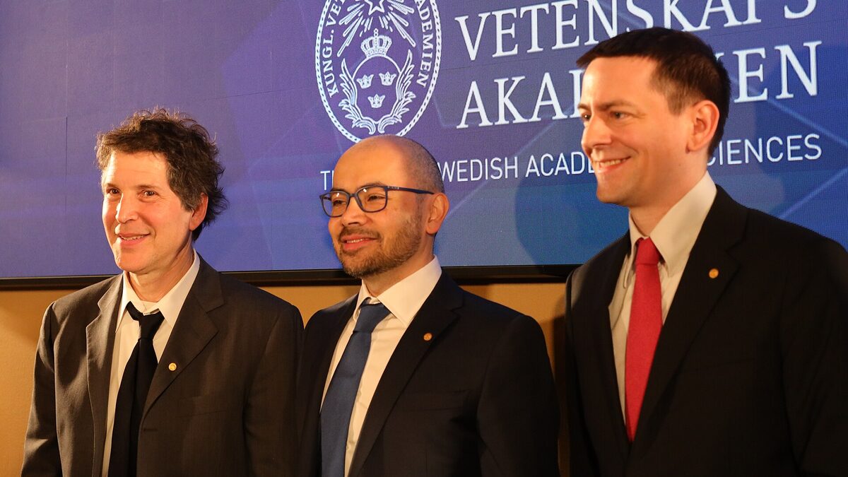 Demis Hassabis stands between David Baker and John Jumper in front of a Royal Swedish Academy of Sciences backdrop at the 2024 Nobel Prize conference