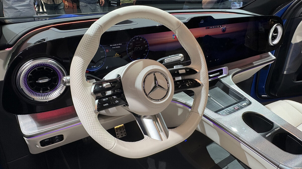 Interior of a Mercedes-Benz GLC showing the redesigned steering wheel with physical rocker switches and rollers next to the wide curved Hyperscreen dashboard display.